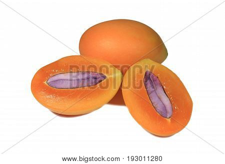 Close-up of fresh ripe Marian Plums orange color whole fruit and cut in half with purple seed on white background