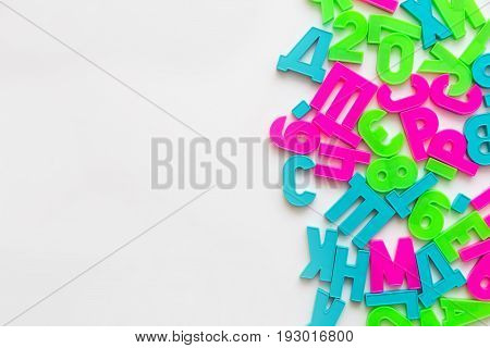 Colorful foam puzzle letters and numbers in kid's hands on a light table. Baby puts puzzle of letters and numbers. Close-up