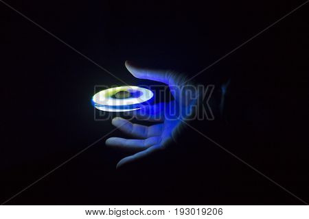Play Fidget spinner spinning and Hand on dark background With Ligtht