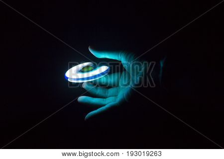 Play Fidget spinner spinning and Hand on dark background With Ligtht