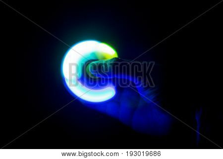 Play Fidget spinner spinning and Hand on dark background With Ligtht