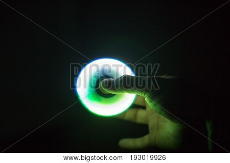 Play Fidget spinner spinning and Hand on dark background With Ligtht
