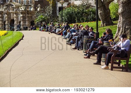 LONDON, ENGLAND, UK - APRIL 24 2017 : unidentified people relax in the park lunch break. Is widespread eating lunch in one of the city parks during the beautiful days