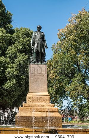 Hobart Australia - March 19. 2017: Tasmania. Bronze statue of Rear Admiral Sir John Franklin shows him looking proudly. Green park background with fountain and blue sky.