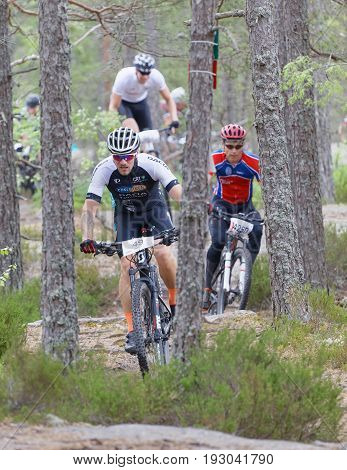 STOCKHOLM SWEDEN - JUNE 11 2017: Group of male mountain bike cyclists in the forest partly hidden of trees at Lida Loop Mountain bike Race. June 11 2017 in Stockholm Sweden