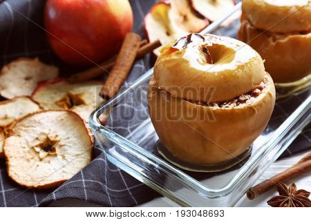 Glass dish with tasty baked apples on table, closeup