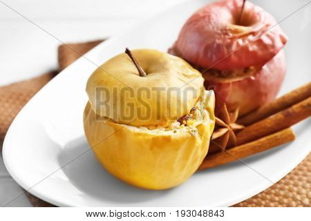 Plate with tasty baked apples and cinnamon on table, closeup