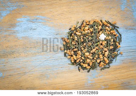 genmaicha green tea with roasted rice, a pile against grunge wood with a copy space