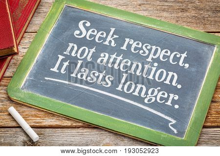 Seek respect, not attention. It last s longer. Motivational text on a slate blackboard with a white chalk and a stack of books.