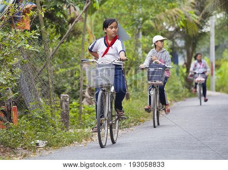 An Binh Island, Vietnam - March 25, 2017 : Vietnamese pioneers go home from school by bicycles on An Binh island, Vinh Long, Vietnam