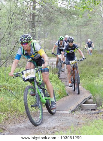 STOCKHOLM SWEDEN - JUNE 11 2017: Female mountain bike cyclist in the forest cycling over a bridge in the forest at Lida Loop Mountain bike Race. June 11 2017 in Stockholm Sweden