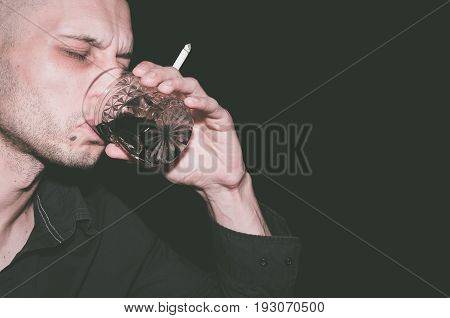 Alcohol and cigarettes. Drunk man drinking alcohol and smoke cigarette. Black background.