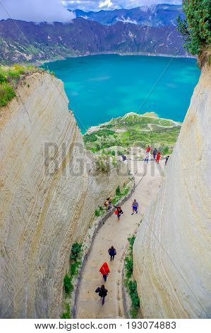 QUITO, ECUADOR - NOVEMBER, 25 2016: Unidentified people walking in a path to enjoy the beautiful and amazing view of lake with a beautiful magenta color of the Quilotoa caldera, . Quilotoa is the western volcano in Andes range and is located in andean reg