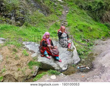 VILLAGE NAGGAR VALLEY KULLU STATE HIMACHAL PRADESH INDIA - APRIL 19 2014: Two grandmothers sit on a stone in small village in Himalayas in north of state Himachal Pradesh.