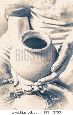 Potter holds more crude to the firing of white clay jug. Sculptor sculpts pots products from white clay. Master keeps on empty hands open earthen vessel. Workshop pottery. Old vintage style.