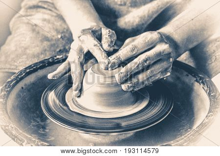Potter hands creating a product from clay on a potter's wheel. Hands close-up master. Old vintage style.
