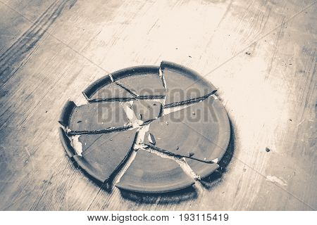 Broken clay plate lying on a wooden table. Old vintage style.