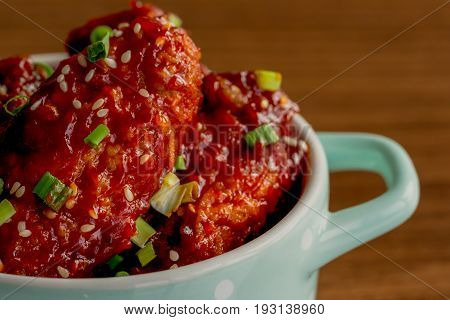 Korean fried chicken wings sprinkled with sesame and scallion in little bowl. Korean barbecue chicken wing delicious moist and spicy. Close up on fried chicken wings in Korean style ready to serve. Homemade Korean chicken wings.