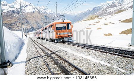ZERMATT, SWITZERLAND - May 16. 2017: Red train climbing up to Gornergrat station on Zermatt, Switzerland. The Gornergrat rack railway is the highest open-air railway in Europe.