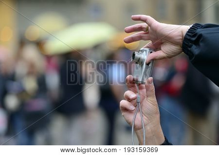 Hands holding a compact digital point-and-shoot photo camera. Taking outdoor pictures with a digital compact camera.