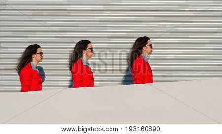 Threefold girl walks between a wall and sheet.