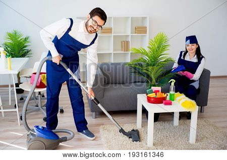 Cleaning service team vaccuuming, dusting and watering plants