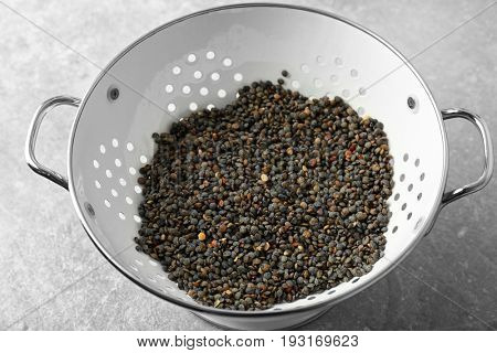 Collander with raw lentils on table, closeup