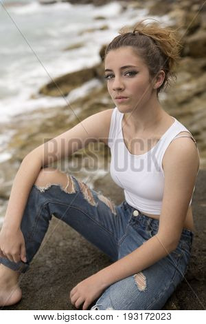 Teenage Girl Sitting On The Rocks.