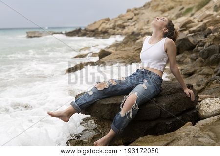 Teenage Girl Sitting On The Rocks.