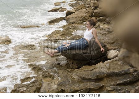 Teenage Girl Sitting On The Rocks.