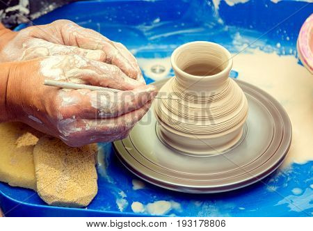 Zaporizhia/Ukraine- May 28, 2017: Charity Family festival: closeup hands of ceramist master creating a pattern on a jar at outdoors pottery workshop