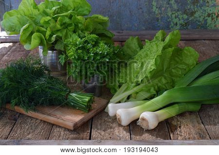 Composition Of Green Herbs And Vegetables. Organic Spring Mix For Salad On Brown Wooden Background.
