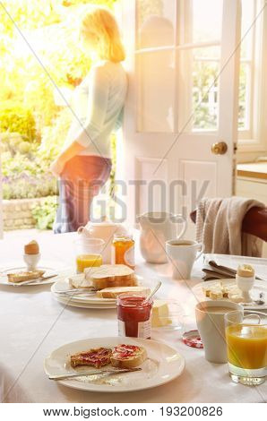 Woman holding tea at the doorway with breakfast table in foreground