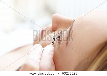 The beautician prolongs and thickens eyelashes.The beautician prolongs and thickens eyelashes.