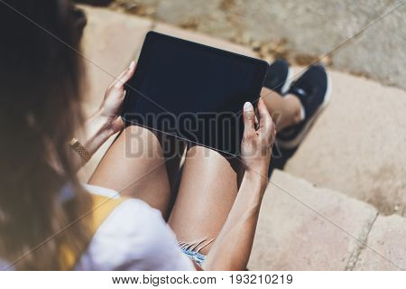 Hipster young girl with bright backpack and vintage camera using tablet or holding gadget planning travel plan. View tourist traveler on background Parc Laberint Barcelona. Mock up for text message