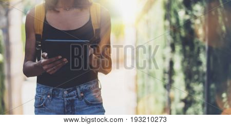 Hipster young girl with bright backpack and vintage camera using tablet or holding gadget planning travel plan. View tourist traveler on background Parc Laberint Barcelona. Mock up for text message