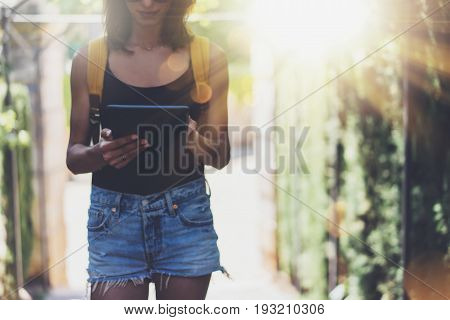 Hipster young girl with bright backpack and vintage camera using tablet or holding gadget planning travel plan. View tourist traveler on background Parc Laberint Barcelona. Mock up for text message