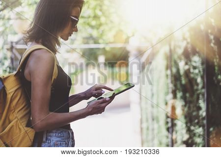 Hipster young girl with bright backpack and vintage camera using tablet or holding gadget planning travel plan. View tourist traveler on background Parc Laberint Barcelona. Mock up for text message