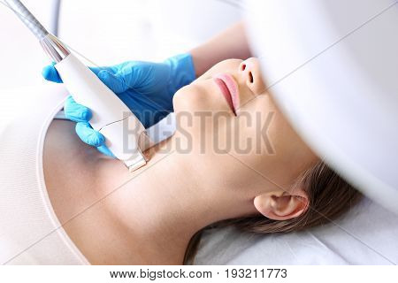 Firming the skin of the neck. The vacuum neck massage using a special head. Woman in the clinic of aesthetic medicine.