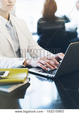 Young woman writing text hands on the open laptop in a cafe on a table with reflection and glare businesswoman working on computer and smartphone in blue tones