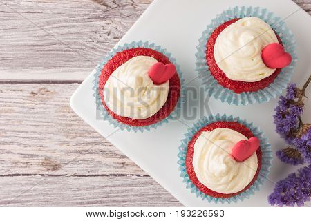 Red velvet heart cupcakes with cream cheese frosting and a red heart for Valentine's Day. Top view with copy space