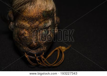 A shrunked human head from ecuador over a dark background.