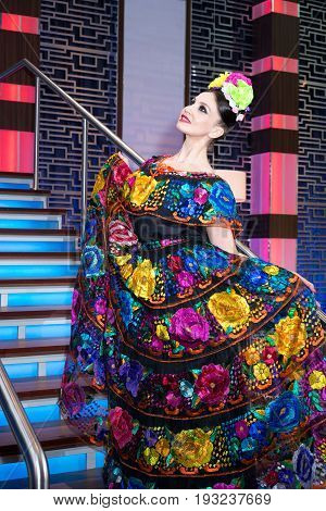 mexican woman in an embroidery traditional dress standing on the staircase