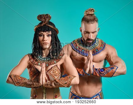 The man and woman in the images of Egyptian Pharaoh and Cleopatra on blue studio background