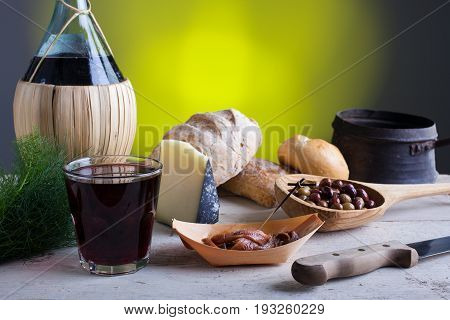 Italian slow food on the white table. Olives cheese bread anchovies and red wine