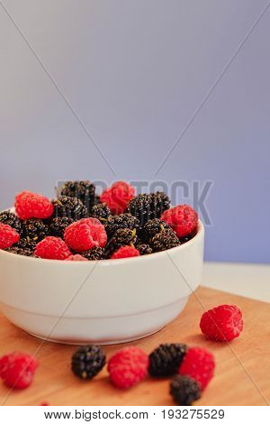 Summer berries in a pialat on wooden background close-up