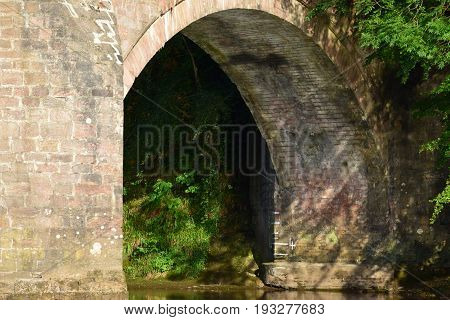 Image of a single arch of a stone built bridge spanning a river