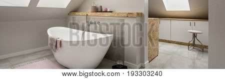 Bathroom in the attic with an oval bathtub and moving on to the utility room with cupboards