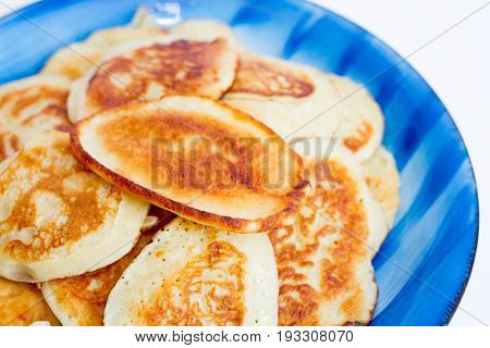 Ruddy freshly cooked pancakes lie on a blue plate on a white background. Isolate.