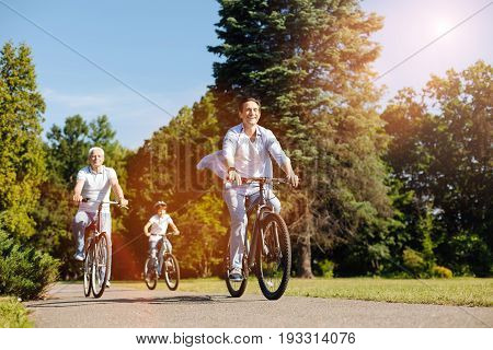 Active days off. Handsome enthusiastic nice man enjoying the weekend with his family while they exploring new routes and riding bicycles